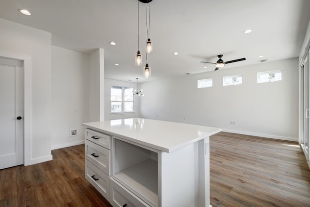 kitchen featuring decorative light fixtures, white cabinets, a kitchen island, dark hardwood / wood-style floors, and ceiling fan with notable chandelier