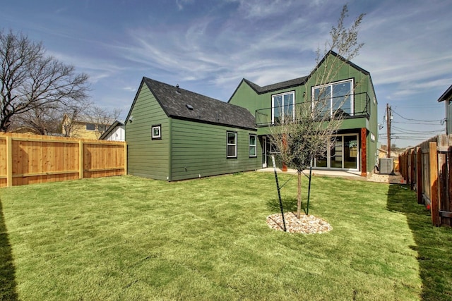 rear view of property featuring a yard, a patio area, and central AC