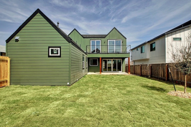 back of house with a patio area and a lawn