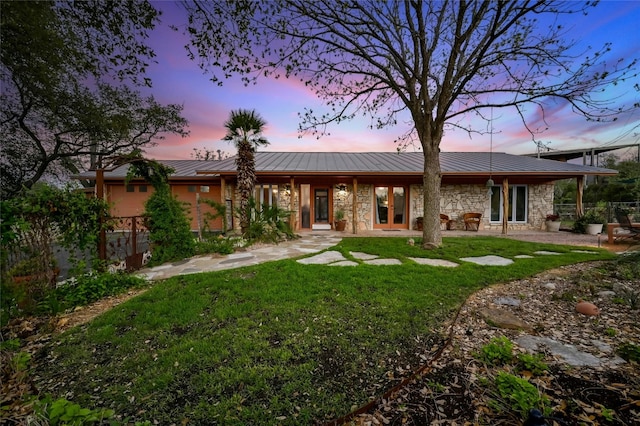 back house at dusk featuring a patio and a yard