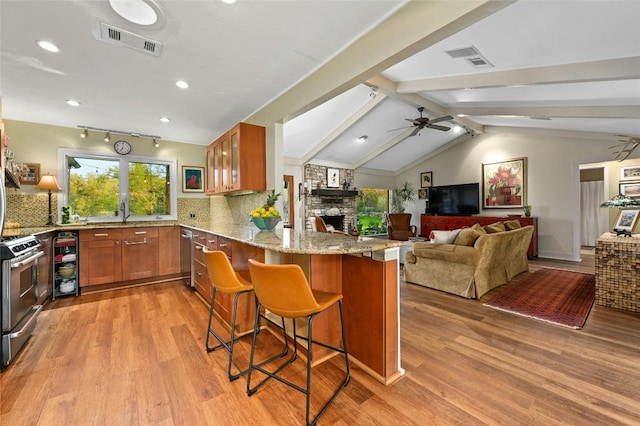 kitchen with a fireplace, ceiling fan, tasteful backsplash, range with two ovens, and lofted ceiling with beams