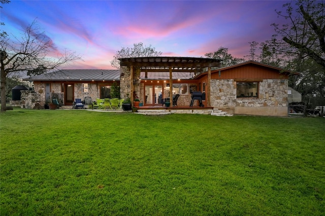 back house at dusk featuring a yard, a pergola, and a patio