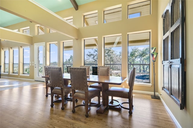 dining area with beamed ceiling, hardwood / wood-style floors, and high vaulted ceiling