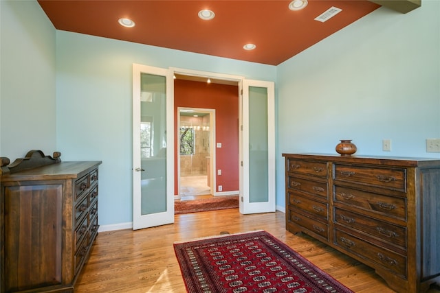 bedroom featuring connected bathroom, light hardwood / wood-style floors, and french doors