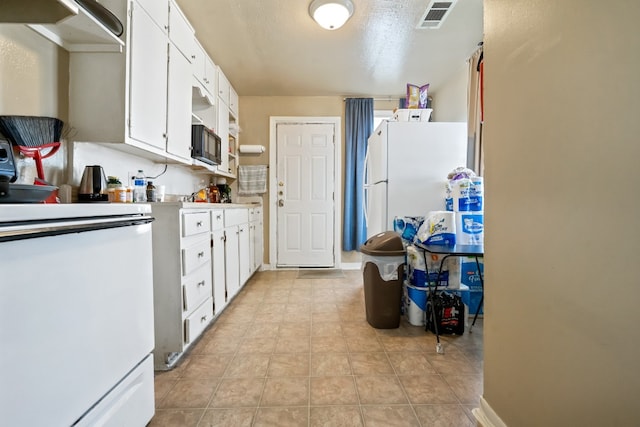 kitchen featuring light tile patterned flooring, white fridge, white cabinets, and a textured ceiling