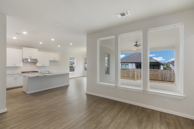 kitchen featuring white cabinets, light hardwood / wood-style floors, ceiling fan, and an island with sink