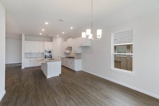 kitchen with appliances with stainless steel finishes, a center island with sink, dark hardwood / wood-style flooring, and decorative light fixtures