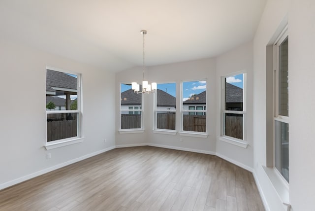 unfurnished dining area with an inviting chandelier and light hardwood / wood-style floors