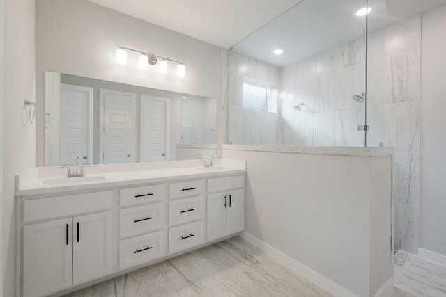 bathroom featuring tiled shower, double sink, and vanity with extensive cabinet space