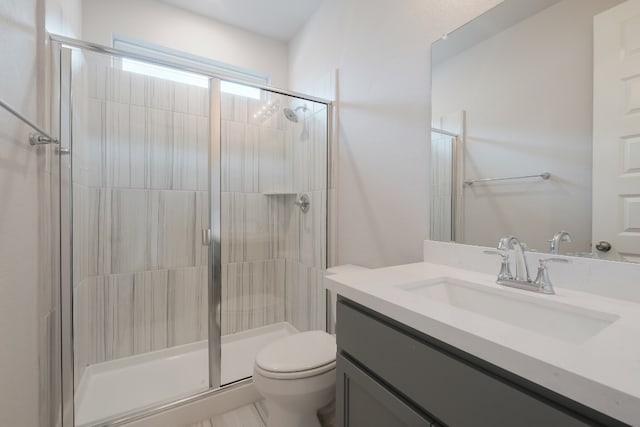 bathroom featuring toilet, a shower with shower door, and vanity with extensive cabinet space