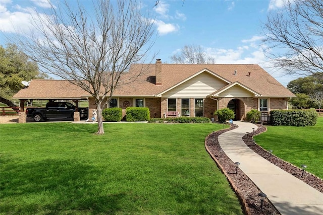 ranch-style home with a front lawn, roof with shingles, a chimney, brick siding, and a carport