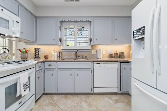 kitchen featuring a sink, white appliances, gray cabinets, decorative backsplash, and light tile patterned floors