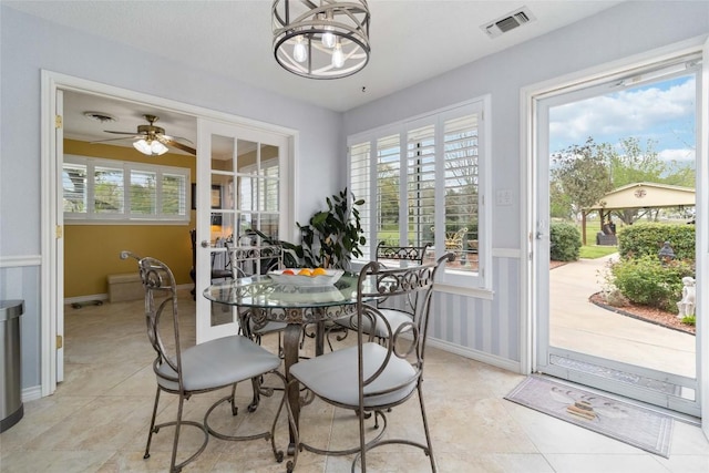 dining space with baseboards, visible vents, ceiling fan with notable chandelier, and a wealth of natural light