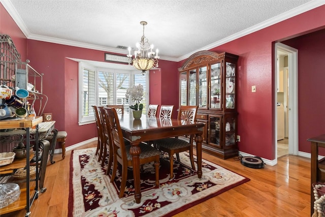 dining room with hardwood / wood-style flooring, ornamental molding, a chandelier, and a textured ceiling