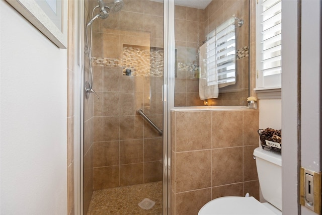 bathroom with a shower with shower door and toilet