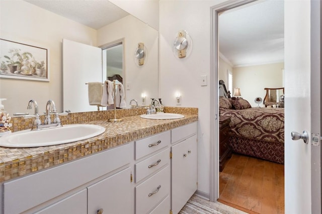 ensuite bathroom featuring double vanity, a sink, connected bathroom, and wood finished floors