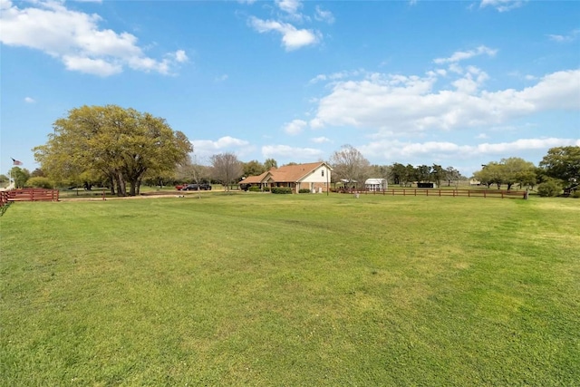 view of yard with fence and a rural view