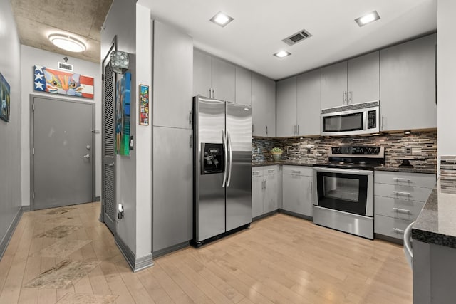 kitchen with light hardwood / wood-style floors, tasteful backsplash, stainless steel appliances, and gray cabinets