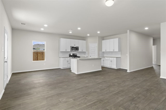 kitchen featuring appliances with stainless steel finishes, dark hardwood / wood-style floors, a kitchen island with sink, and white cabinetry