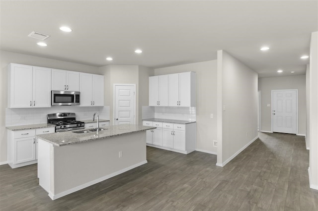 kitchen featuring light stone countertops, a center island with sink, white cabinets, appliances with stainless steel finishes, and sink