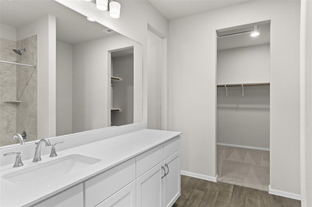 bathroom with tiled shower, vanity, and hardwood / wood-style flooring