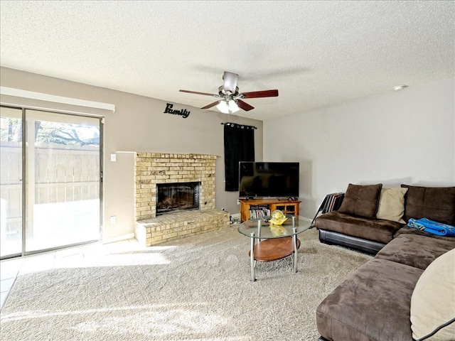 living room with ceiling fan, a textured ceiling, carpet flooring, and a brick fireplace