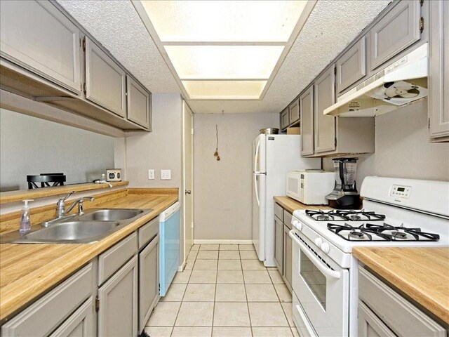 7825 Beauregard Cir Unit 5, Austin, TX 78745 - kitchen with white appliances, under cabinet range hood, butcher block counters, light tile patterned floors, and gray cabinets