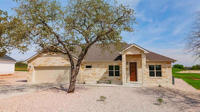 view of front of house featuring driveway, a shingled roof, an attached garage, and stone siding