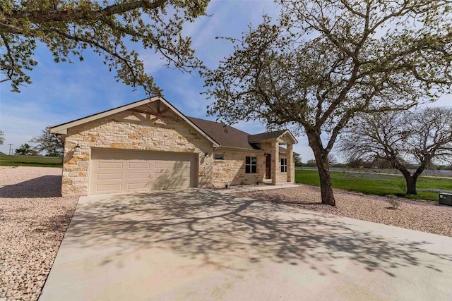 view of front facade featuring an attached garage, driveway, and stone siding