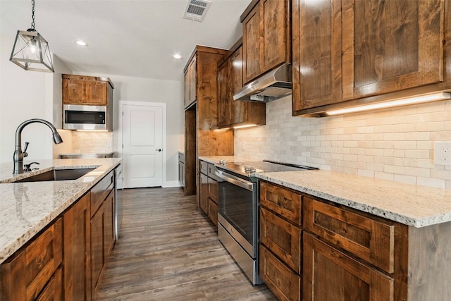 kitchen with stainless steel appliances, decorative light fixtures, dark hardwood / wood-style floors, extractor fan, and sink