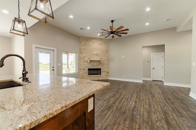 kitchen with a fireplace, light stone countertops, ceiling fan, dark hardwood / wood-style floors, and sink