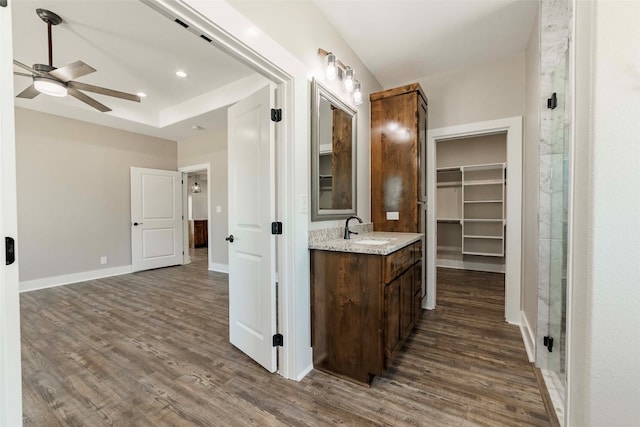 bathroom with ceiling fan, a shower with shower door, hardwood / wood-style flooring, and vanity