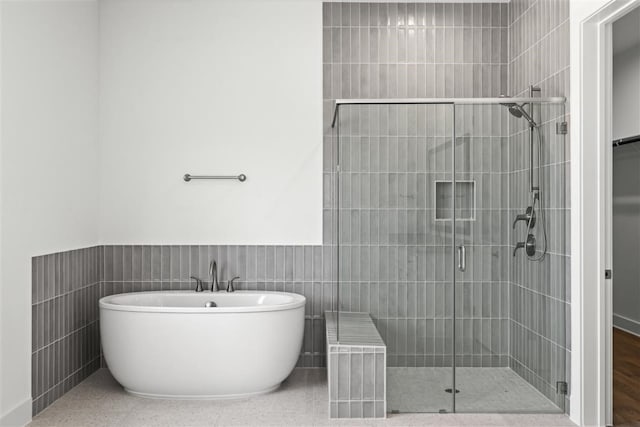 bathroom featuring separate shower and tub and tile walls