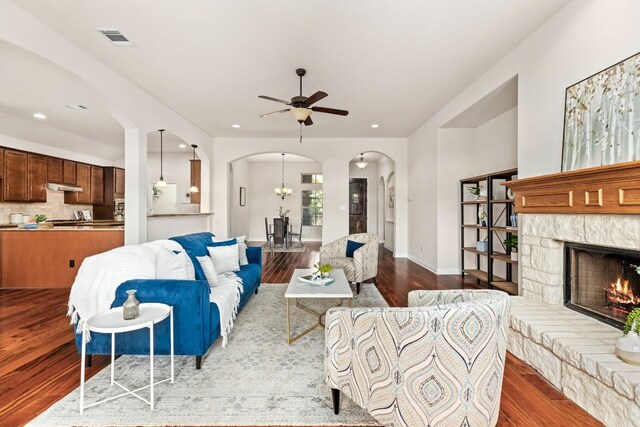 living room featuring ceiling fan, a stone fireplace, and hardwood / wood-style flooring