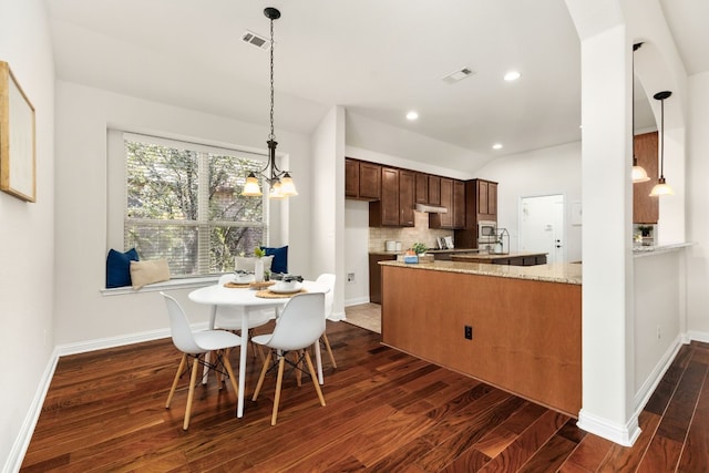 kitchen featuring tasteful backsplash, hanging light fixtures, light stone countertops, and dark hardwood / wood-style floors