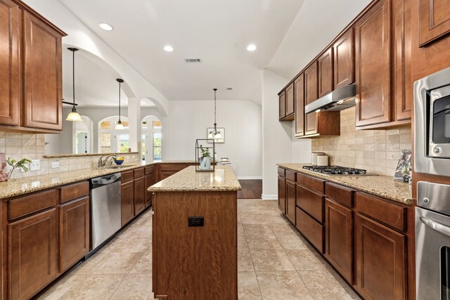 kitchen with appliances with stainless steel finishes, tasteful backsplash, a center island, and light hardwood / wood-style floors