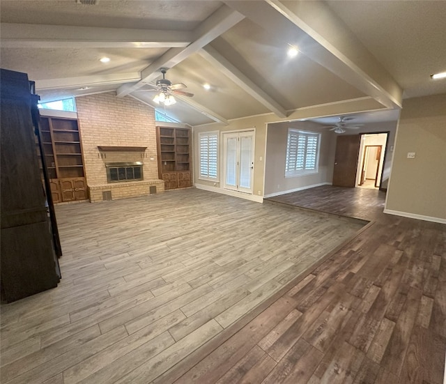 interior space featuring ceiling fan, lofted ceiling with beams, a fireplace, and hardwood / wood-style floors