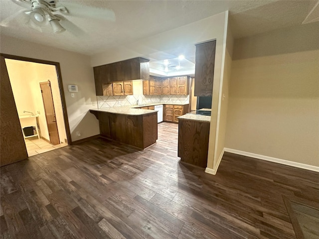 kitchen with backsplash, dark hardwood / wood-style floors, ceiling fan, and sink