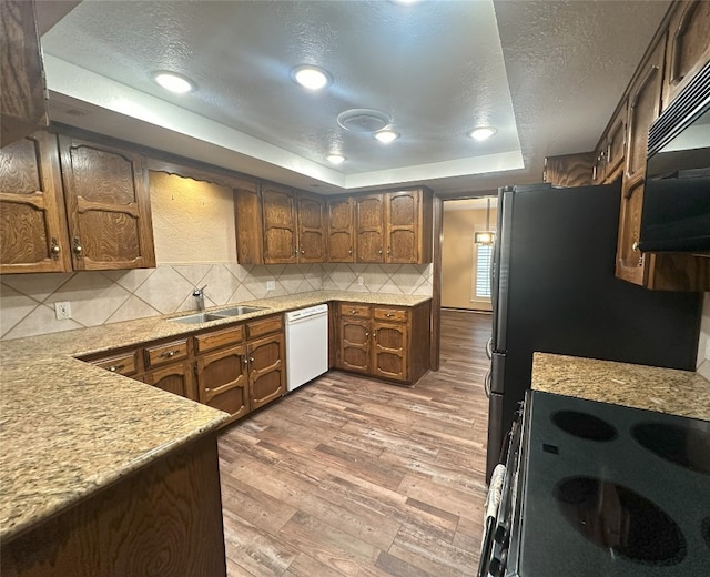 kitchen with tasteful backsplash, built in microwave, white dishwasher, hardwood / wood-style flooring, and a tray ceiling