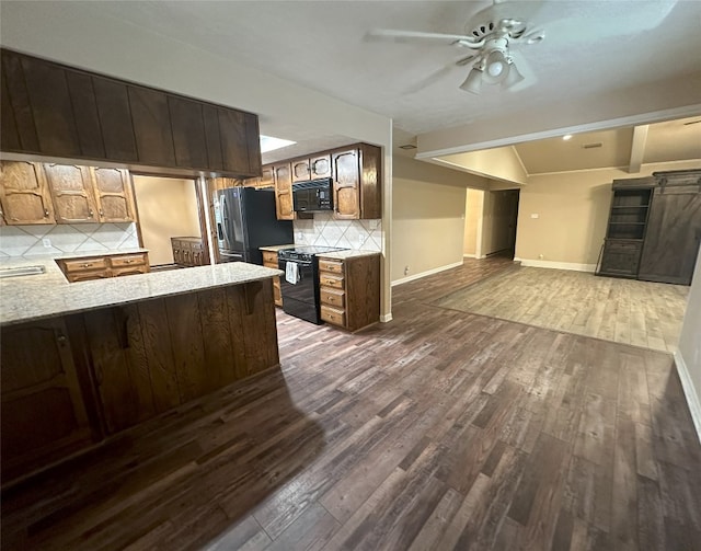 kitchen with ceiling fan, kitchen peninsula, dark wood-type flooring, black appliances, and backsplash