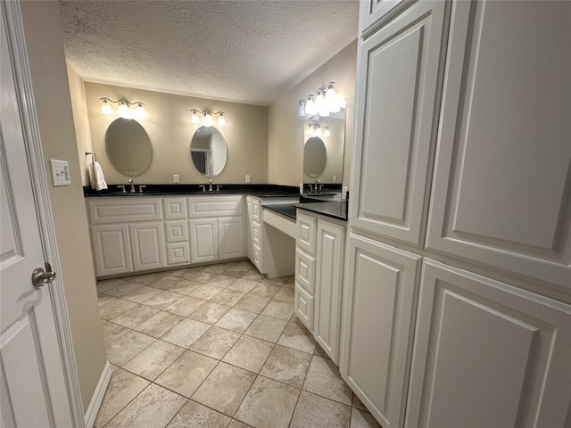 bathroom with a textured ceiling, tile floors, and double vanity