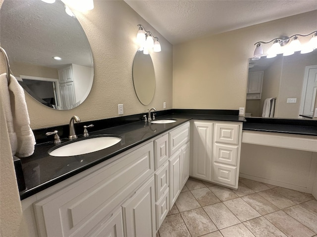 bathroom featuring a textured ceiling, dual sinks, large vanity, and tile flooring