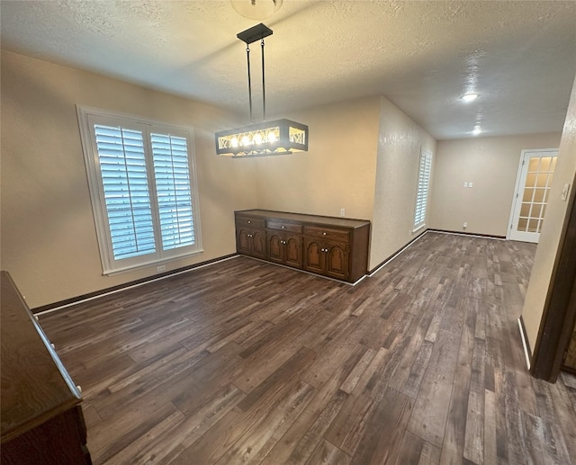 unfurnished dining area featuring a textured ceiling and dark hardwood / wood-style flooring