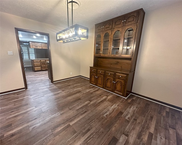 unfurnished dining area with dark hardwood / wood-style flooring and a textured ceiling