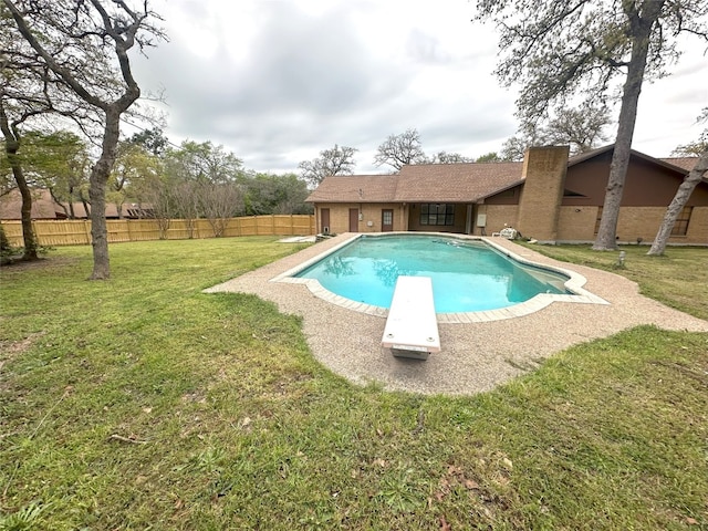 view of pool featuring a lawn and a diving board