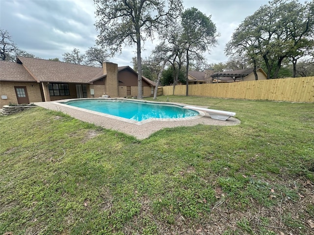 view of pool with a lawn and a diving board