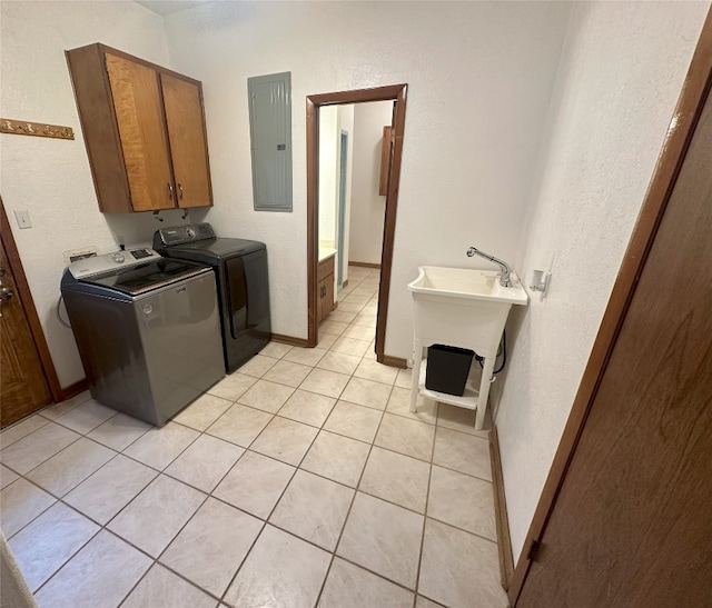 laundry area featuring light tile floors, cabinets, sink, and independent washer and dryer