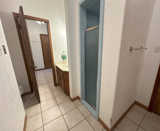 bathroom with tile flooring, an enclosed shower, toilet, and vanity