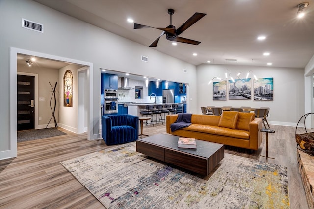 living room with ceiling fan, sink, and light hardwood / wood-style floors