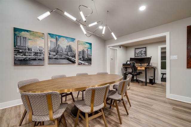 dining room with an inviting chandelier, vaulted ceiling, and light wood-type flooring